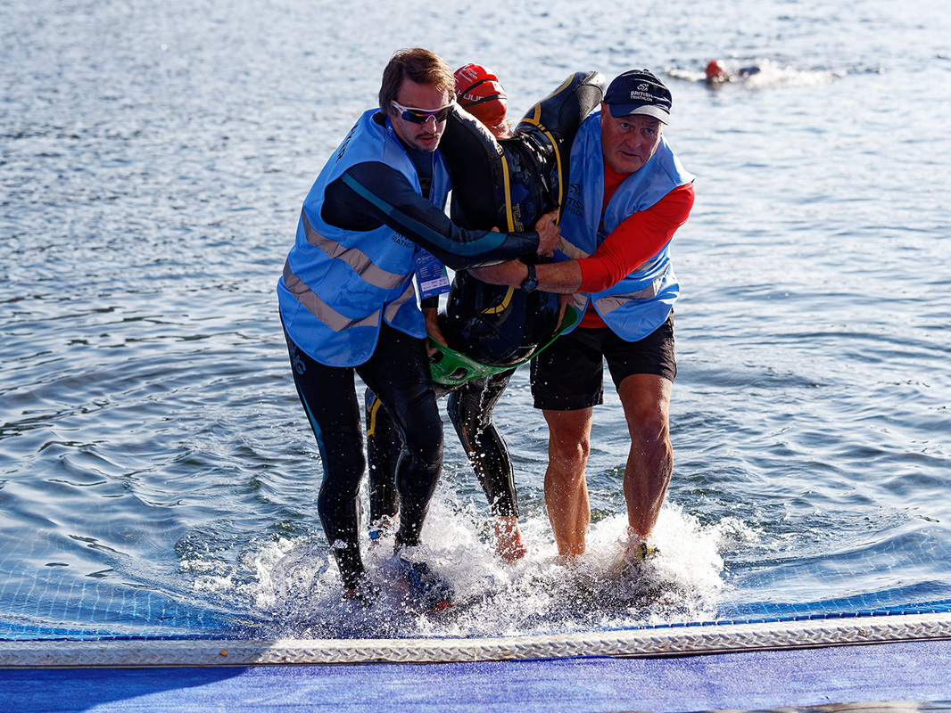 volunteers assist an athlete exiting the swim