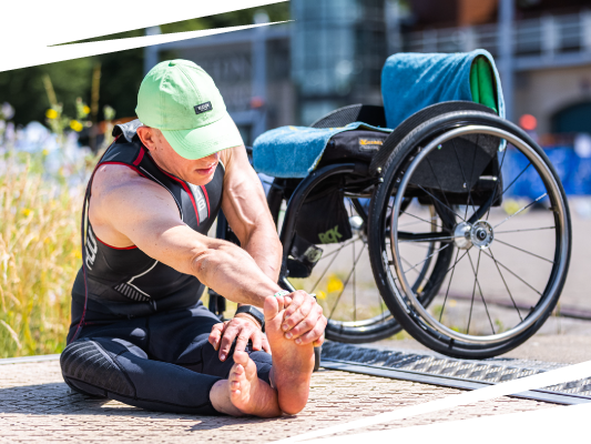 Male athlete stretching on the floor in front of wheelchair