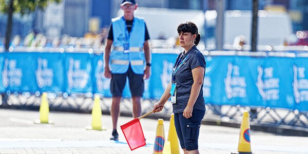 female technical official stood with red flag at the dismount line of an event
