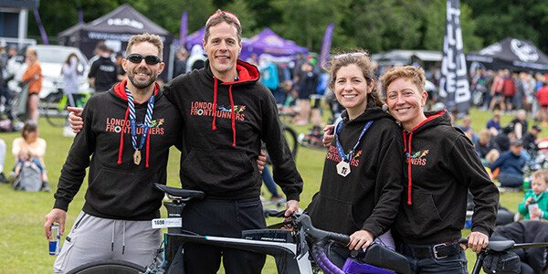 group of people posing with medals and bikes after finishing an event